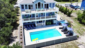 A multi-story house with a pool, outdoor seating, and a view of the surrounding area.