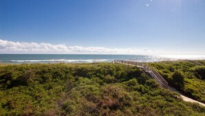 A coastal landscape with a wooden boardwalk leading to the beach, surrounded by dense greenery. - OCEANFRONT, Ocean Views, Sun Decks, Close to Beach Access, SA47, Lazy Bones (Duck)