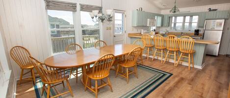 A dining area with a wooden table and chairs, a kitchen with light blue cabinets, and a view of the outside.