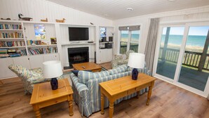 A cozy living room with a fireplace, a television, and a large window overlooking the beach. - OCEANFRONT, Ocean Views, Sun Decks, Close to Beach Access, SA47, Lazy Bones (Duck)