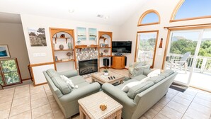Una sala de estar con un sofá, un televisor y un balcón con mobiliario exterior.
