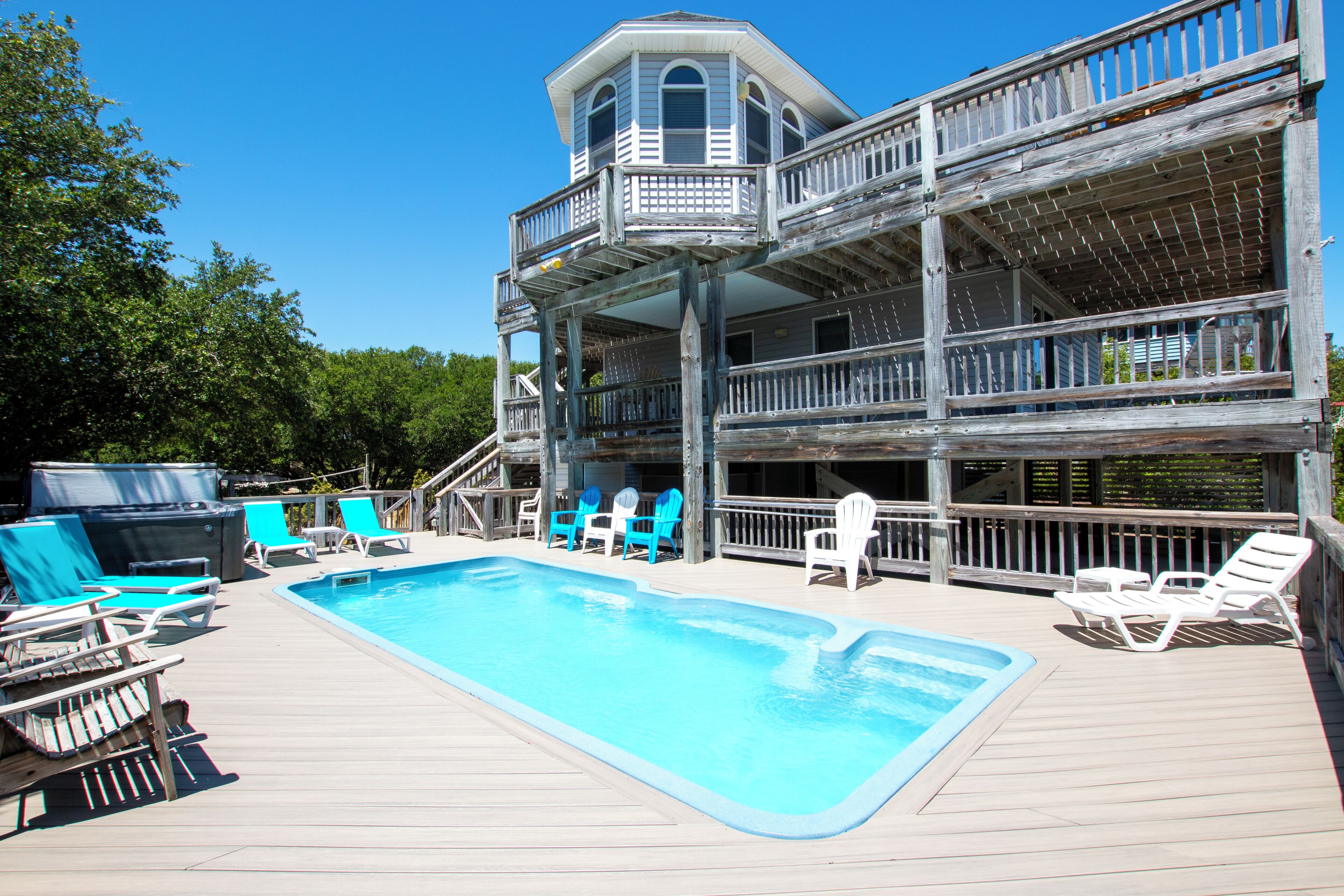 A wooden deck with a pool, multiple levels of balconies, and outdoor seating.
