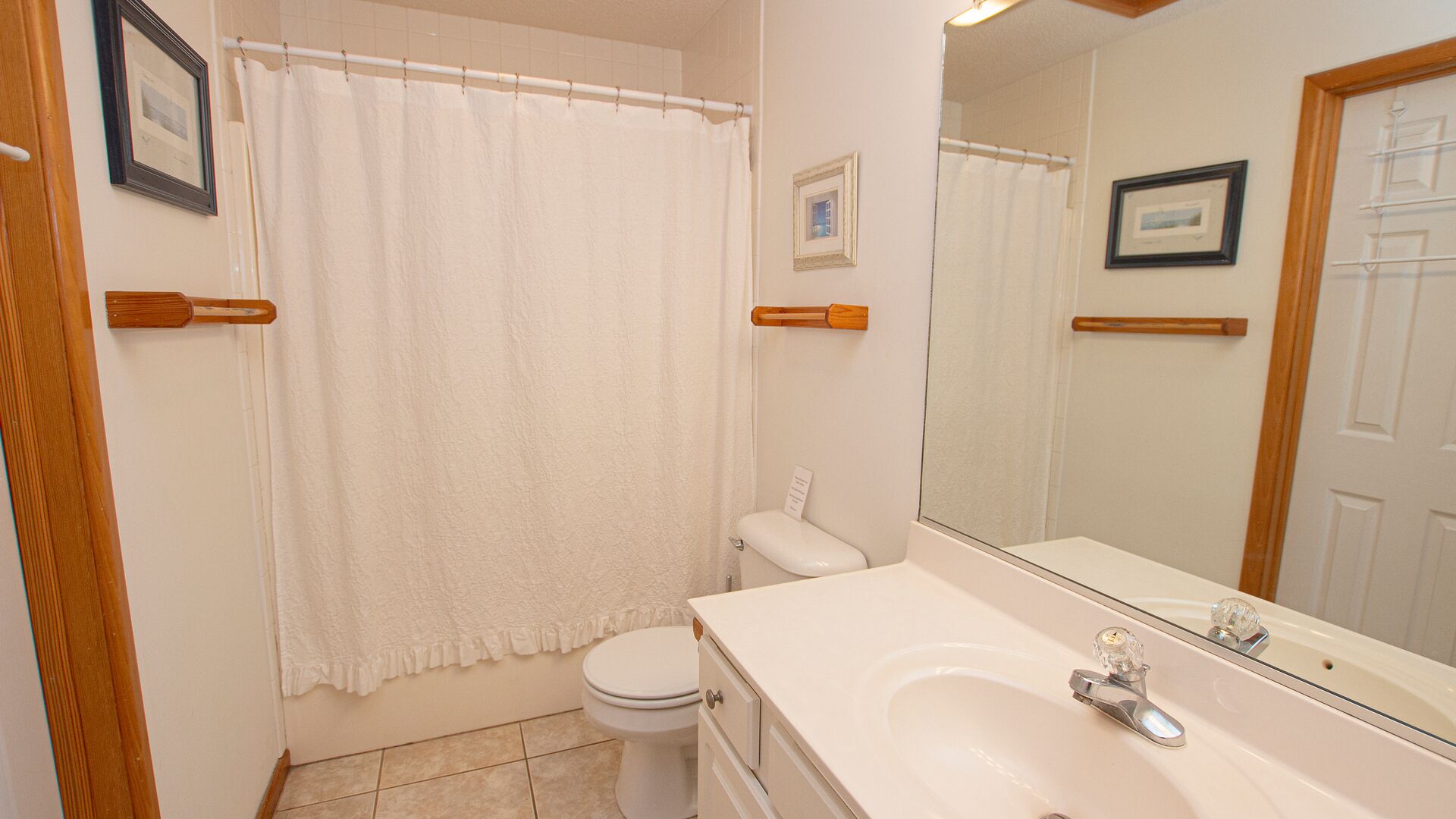Un baño con inodoro blanco, lavamanos con espejo y cortina de ducha.