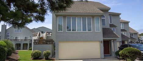 A two-story residential house with a garage, a small front yard, and a staircase leading to an upper level.