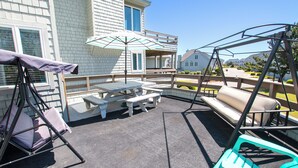 A patio area with a swing set, picnic table, and outdoor seating.