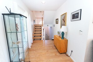 A hallway with a staircase, a wooden cabinet, and a lamp.
