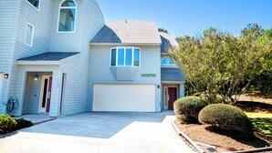 A two-story residential building with a garage, a driveway, and a well-maintained lawn.