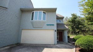 A two-story house with a garage, a small porch, and a street sign indicating the address. - Oceanside, Community Pool, Community Amenities, 677, Windswept II (Corolla)