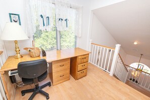 Ett rum med ett skrivbord, en stol, en lampa och ett fönster med persienner.