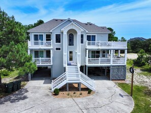 A two-story house with a balcony on the second floor, a covered front porch, and a driveway leading to the entrance.