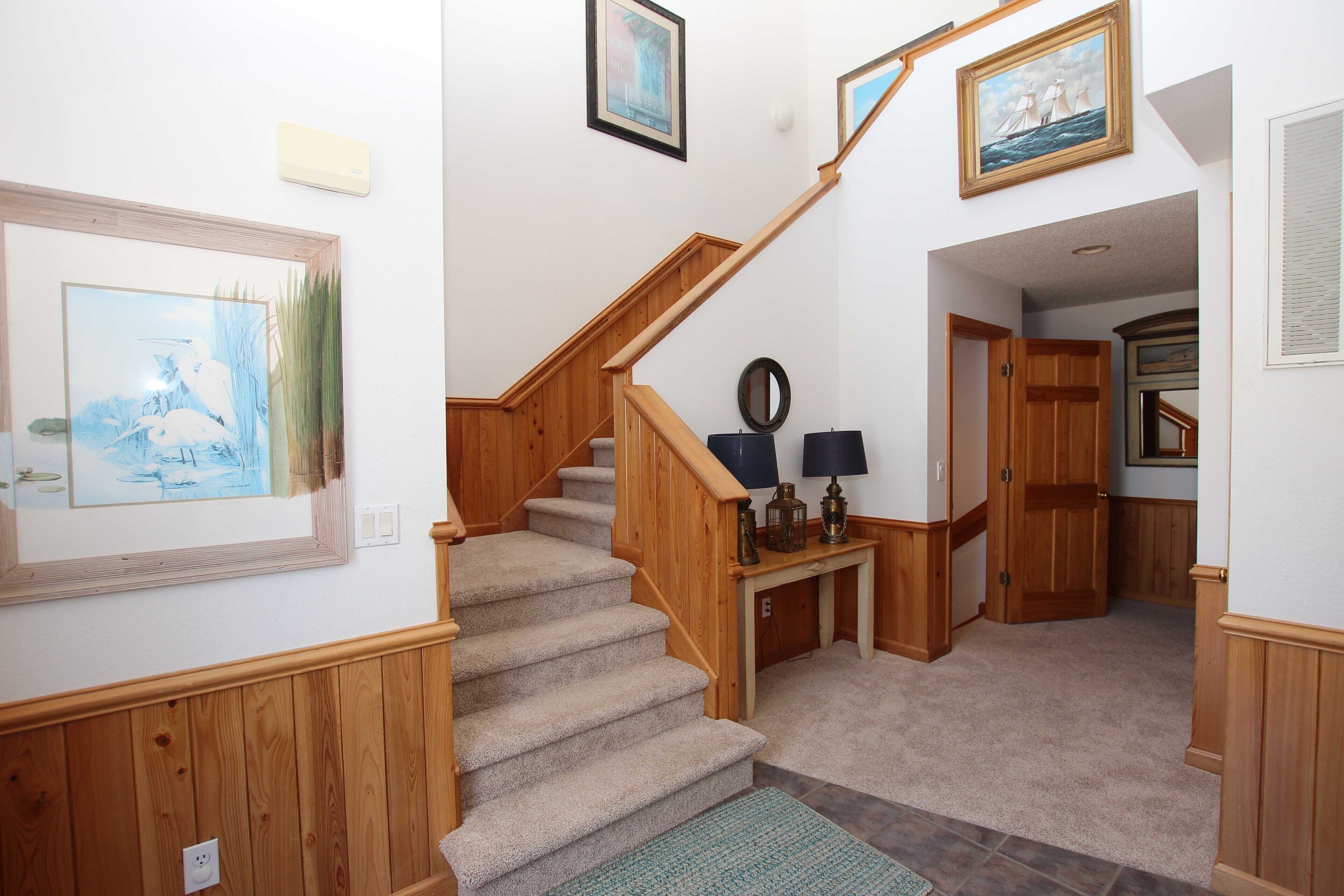 A staircase with wooden railings and a carpeted floor leading to a hallway.