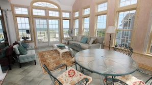 A spacious living room with a large glass table, comfortable seating, and a view of the ocean through large windows. - OCEANFRONT, Pool, Ocean Views, Rec Rm, PI198, Key Largo (Corolla)