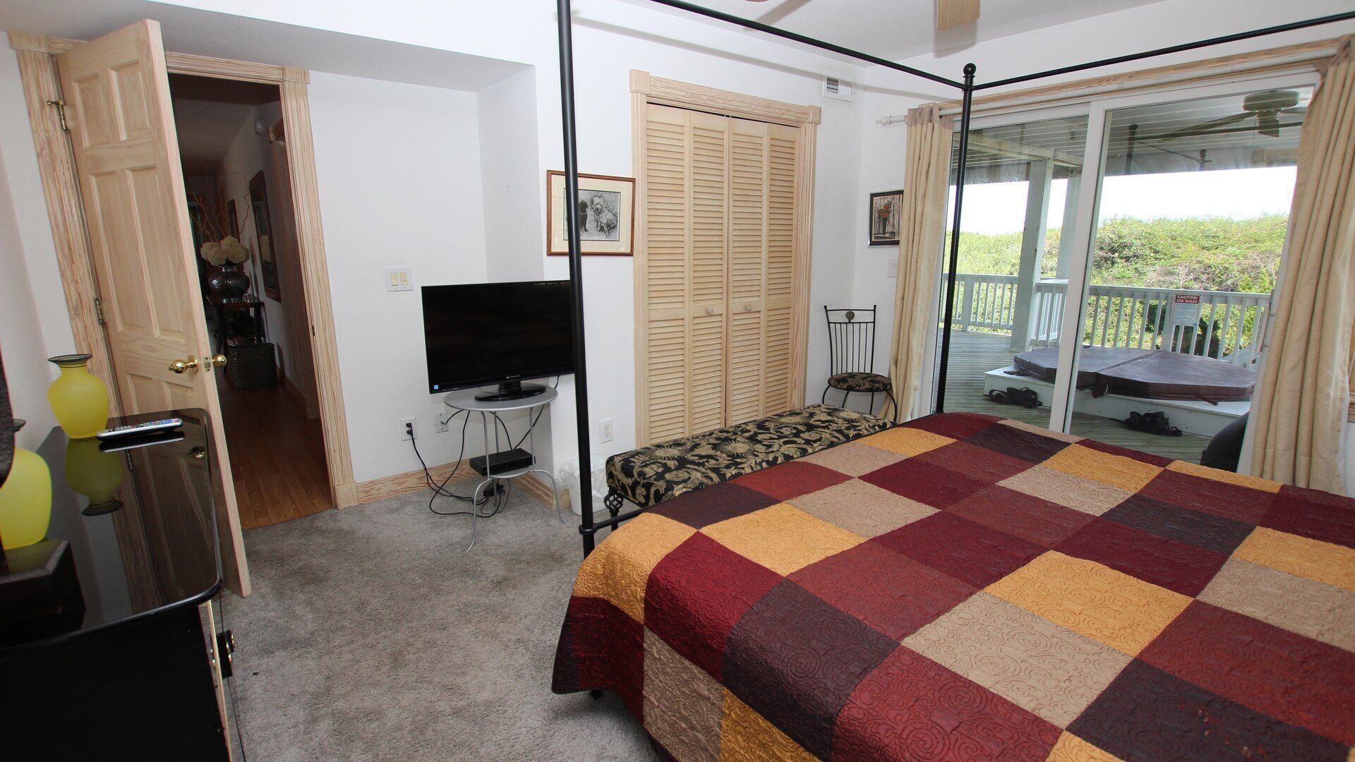 A bedroom with a bed, a television, a wardrobe, and a balcony with a view.