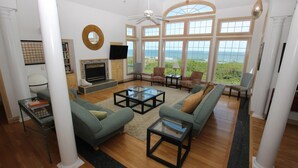 A spacious living room with a fireplace, comfortable seating, and large windows offering a view of the ocean. - OCEANFRONT, Pool, Ocean Views, Rec Rm, PI198, Key Largo (Corolla)
