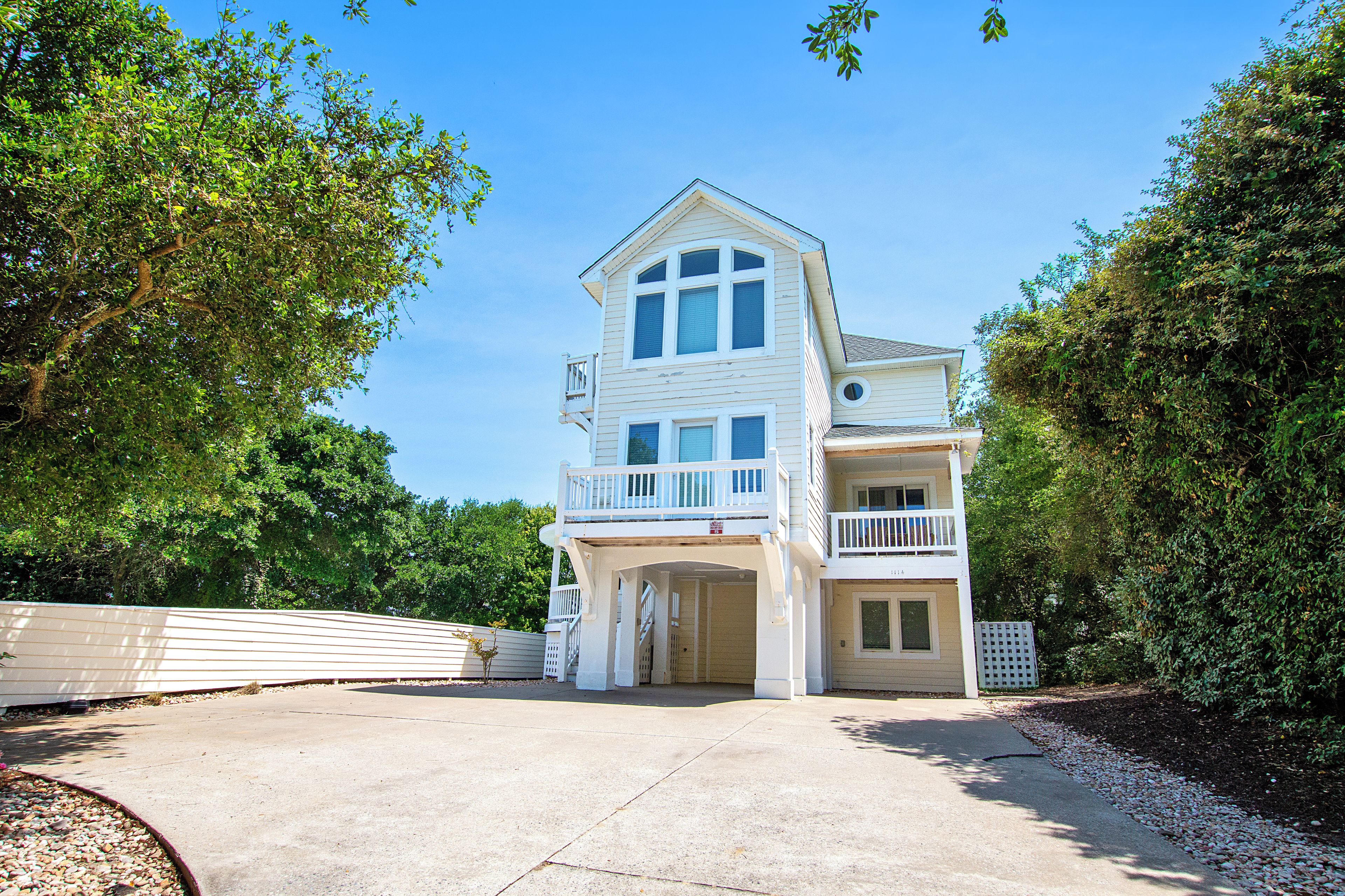 Une maison à deux étages avec un balcon au deuxième étage, un garage et une allée.