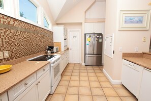 Cozinha moderna com revestimento de azulejos, eletrodomésticos de aço inoxidável e vista para o exterior pela janela.