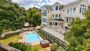 A large two-story house with a swimming pool, a covered hot tub, and a fenced backyard.
