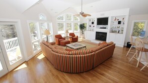 A spacious living room with a large striped sofa, a fireplace, and a television.
