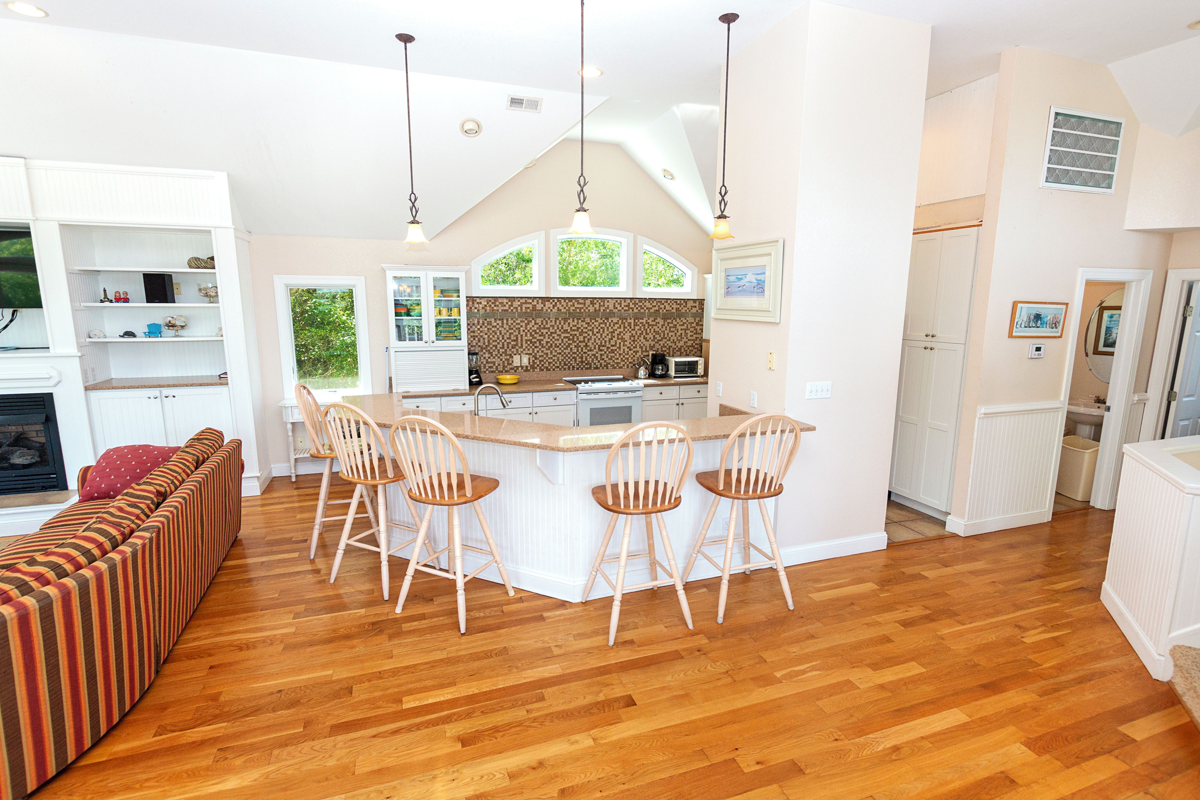 A spacious kitchen with a central island, wooden chairs, and a built-in seating area with a sofa.