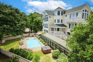 A large two-story house with a swimming pool, a covered patio, and a fenced backyard.