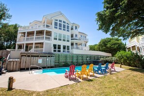 A multi-story building with a pool area, including a hot tub and lounge chairs.