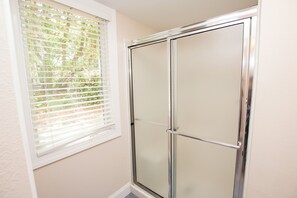 A bathroom with a shower, a window with blinds, and a door. - Oceanside, Community Amenities, Prv Pool, Rec Rm, 5, Carolina on my Mind (Corolla)