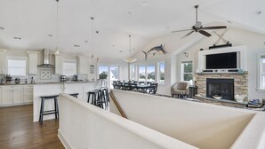 A spacious kitchen with white cabinets, a dining area with a high ceiling fan, and a fireplace. - Oceanside, Priv Pool, ELEV, Hot Tub, Keyless entry, BH3, Knot 4 Sail (Corolla)