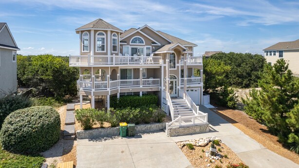 A two-story house with a balcony, a stone pathway, and a small garden area.