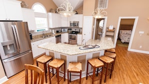 A modern kitchen with white cabinets, stainless steel appliances, and a central island with bar stools.
