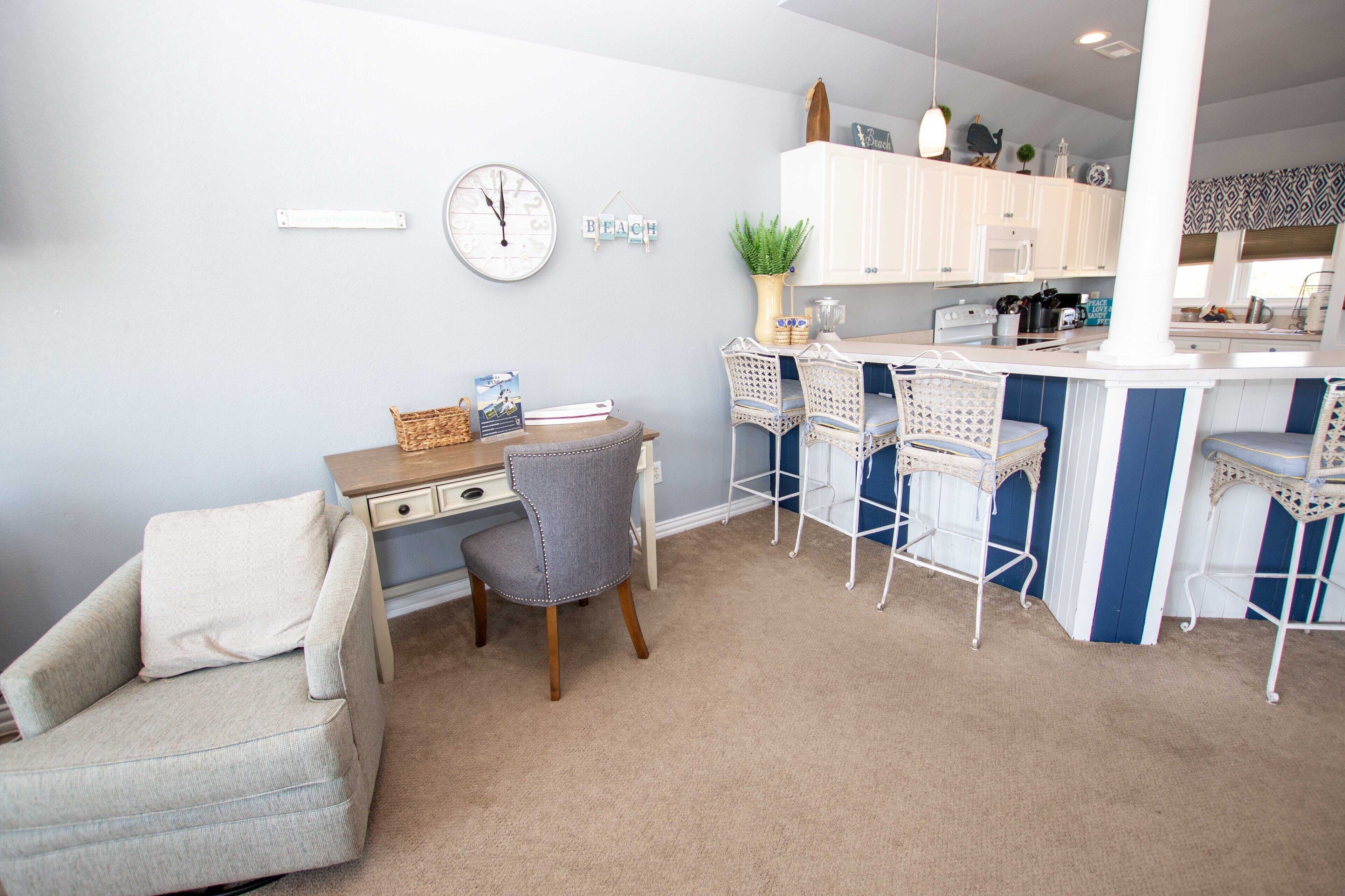 A modern kitchen with white cabinets, a dining area with blue and white chairs, and a small island.