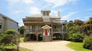 A two-story wooden house with a red door, a balcony on the upper floor, and a covered porch. - Semi-Oceanfront, Close to Beach, Dogs Welcome, SA8, Berry (Duck)