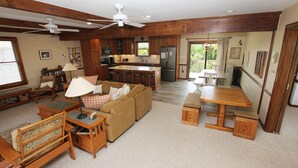 A spacious living room with a sofa, a coffee table, and a wooden dining table. There is a kitchen area with a refrigerator, microwave, and bar stools. - Semi-Oceanfront, Close to Beach, Dogs Welcome, SA8, Berry (Duck)