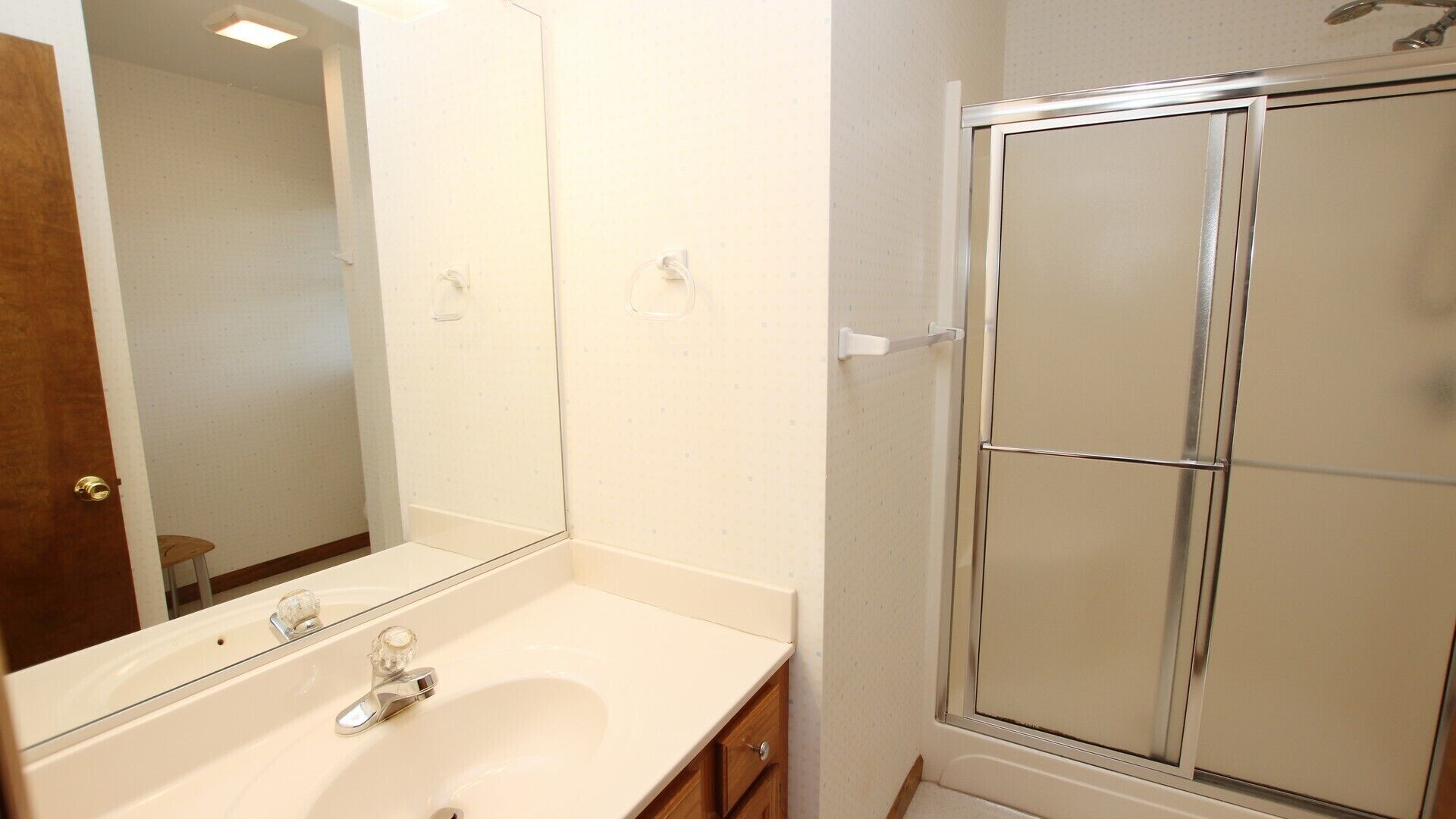 A bathroom with a white sink, a mirror, and a glass shower enclosure.