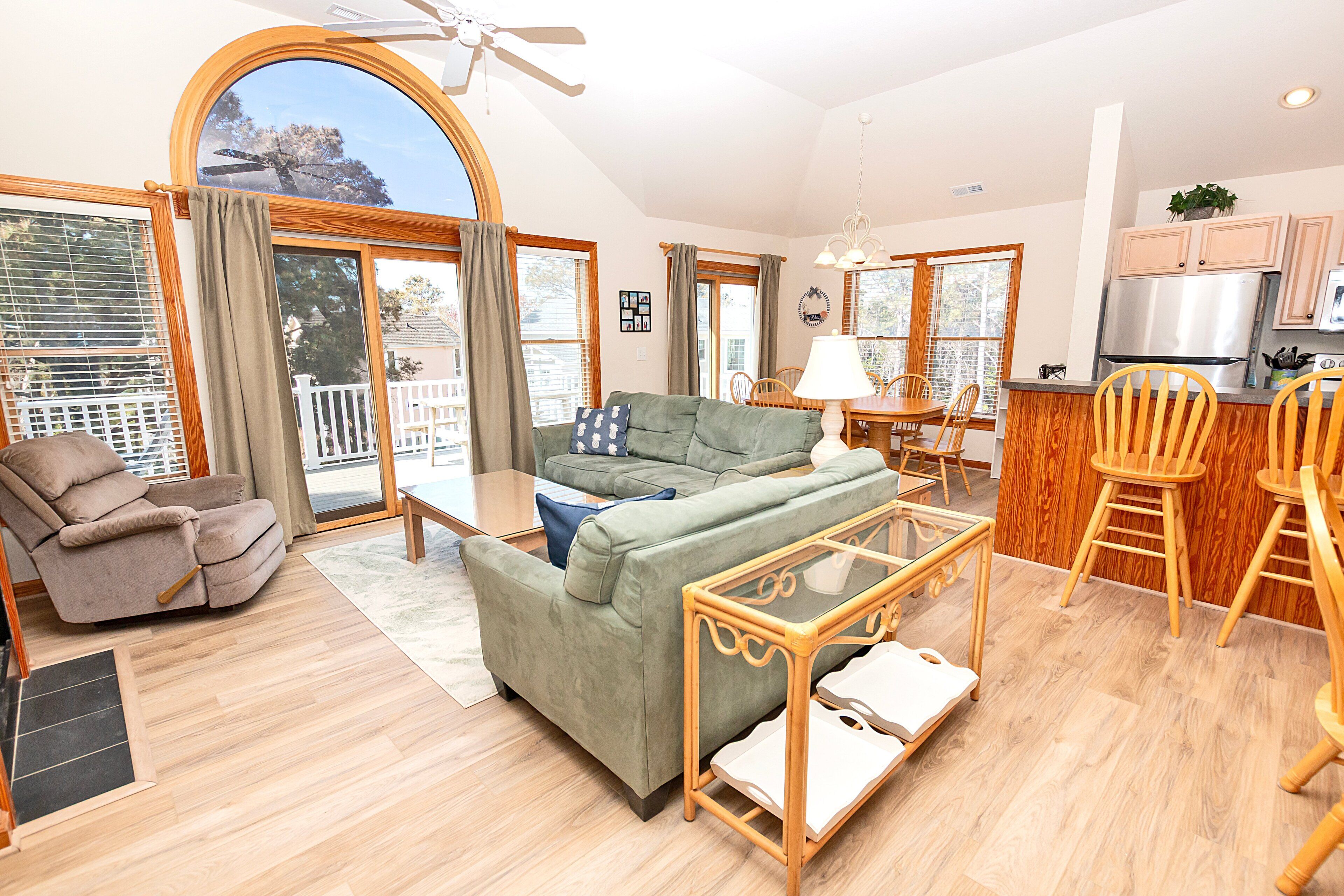 A spacious living area with a sofa, a recliner, a glass coffee table, and a dining table with chairs.