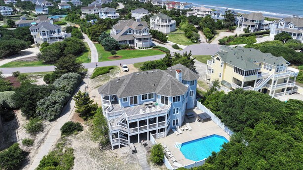 An aerial view of a coastal residential area with houses, a swimming pool, and a beach in the background. - Oceanside, 7 BRs, Private Pool, Den, Rec Rm, 350 ft to Beach access, PI54, Fore Sea Suns (Corolla)