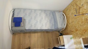 A compact room with a bed, a small table, and a wooden floor. - A46 Foresteria Lombarda (Monza)