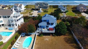 A large house with a pool, a covered patio, and a view of the ocean.