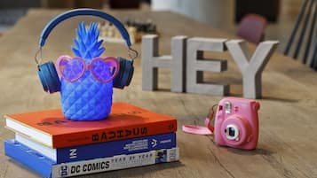 A stack of books, a camera, and headphones on a wooden table.