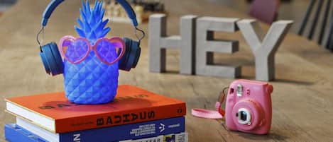 A stack of books, a camera, and headphones on a wooden table.