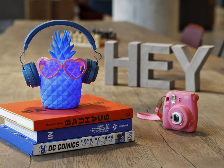 A stack of books, a camera, and headphones on a wooden table.