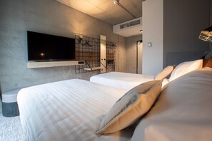 Una habitación de hotel moderna con dos camas, un televisor de pantalla plana montado en la pared y un estante empotrado.