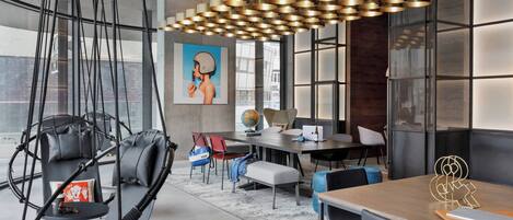 A modern office space with a hanging chair, a large table, and a unique pendant light.