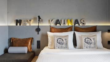 Una habitación de hotel moderna con cama, sofá e iluminación empotrada.