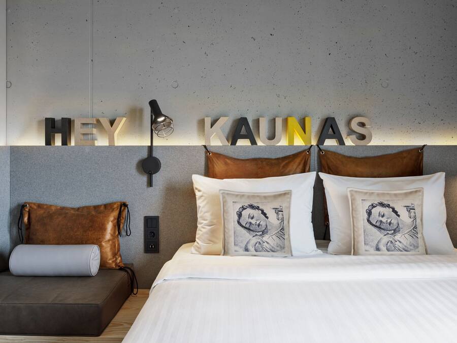 Een moderne hotelkamer met een bed, een bank en een wandlamp.