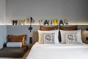 Una habitación de hotel moderna con cama, sofá e iluminación empotrada.