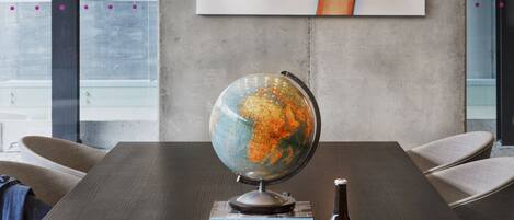 Una habitación moderna con una mesa de madera oscura, un globo terráqueo, una botella y auriculares.