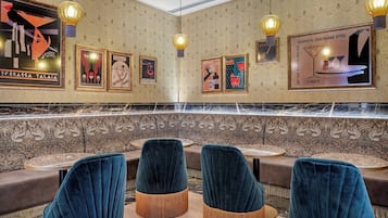 A restaurant interior with velvet chairs, a marble bar, and wall art.
