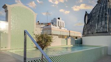 A modern building with a pool area, featuring a checkered tile pattern and a statue.