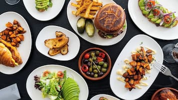 A variety of dishes including a burger, fries, and a salad on a black table.