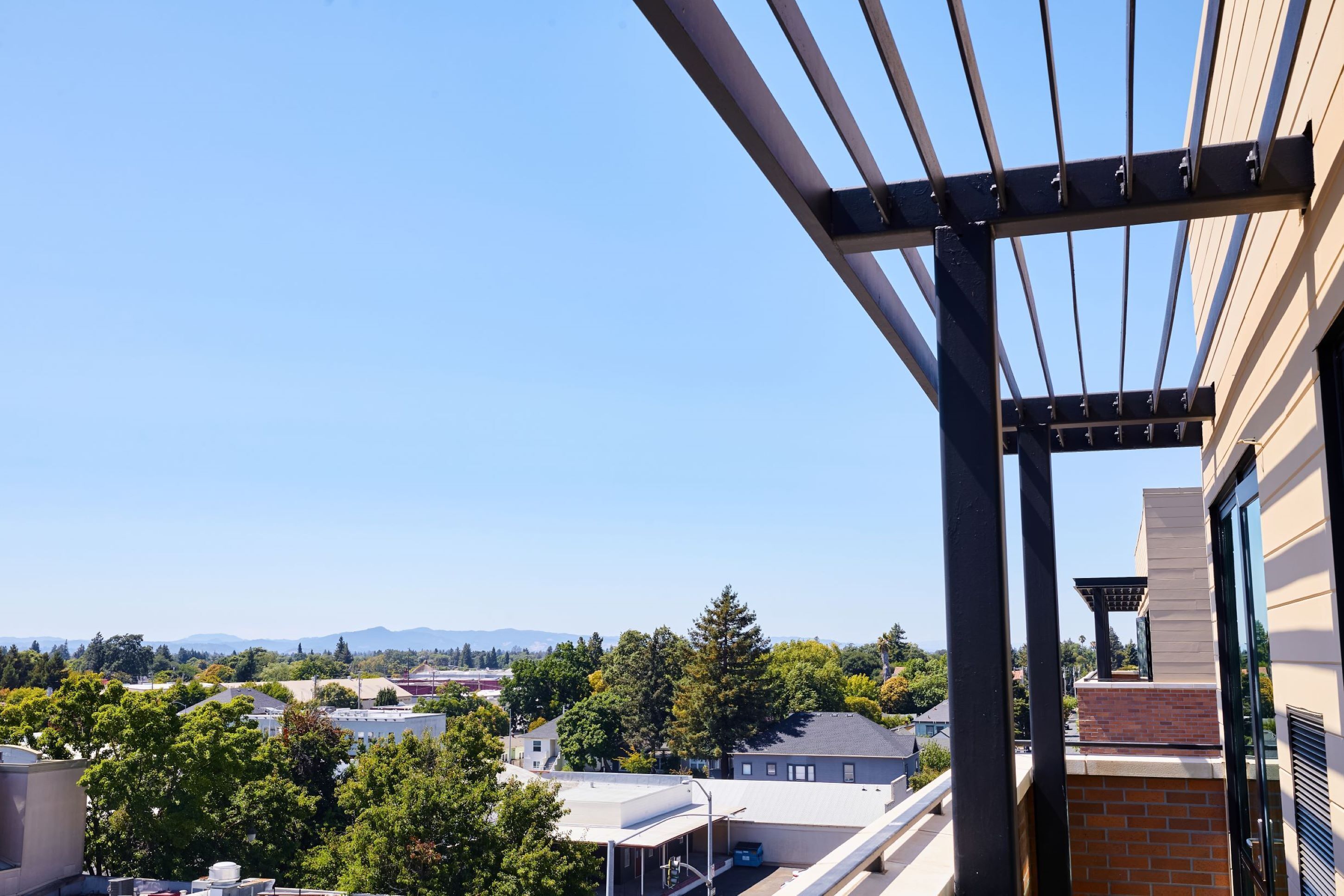 Un balcón con vista a una zona residencial y montañas al fondo.